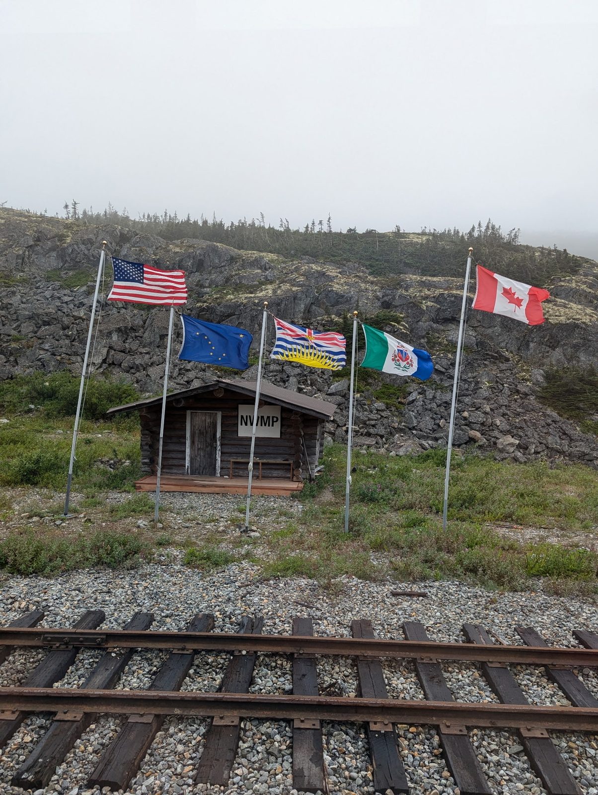 Historic NWMP cabin at the White Pass summit flying US, Alaska, BC, Yukon, and Canada flags
